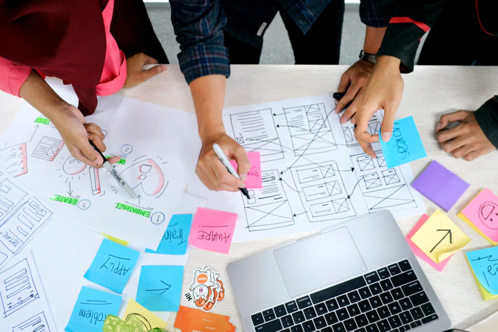 Person writing on white paper to sketch out UI design during a meet-up.